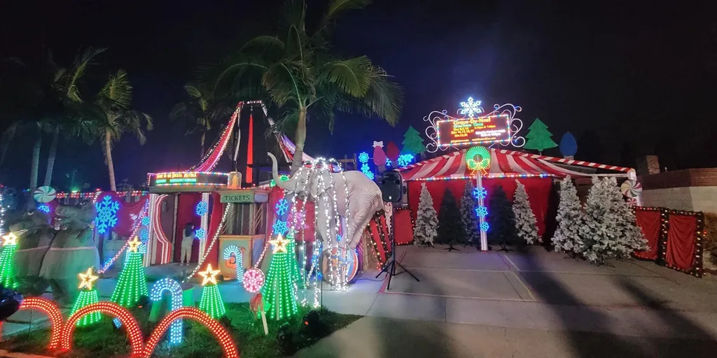 The light show at night: a candy-striped circus tent, a lit elephant, glowing candy canes and Christmas trees, and a marquee sign