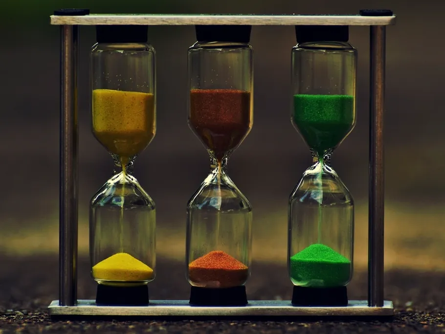 Three hourglasses with yellow, red and green sand running side by side