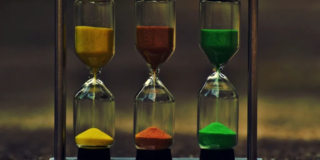 Three hourglasses with yellow, red and green sand running side by side
